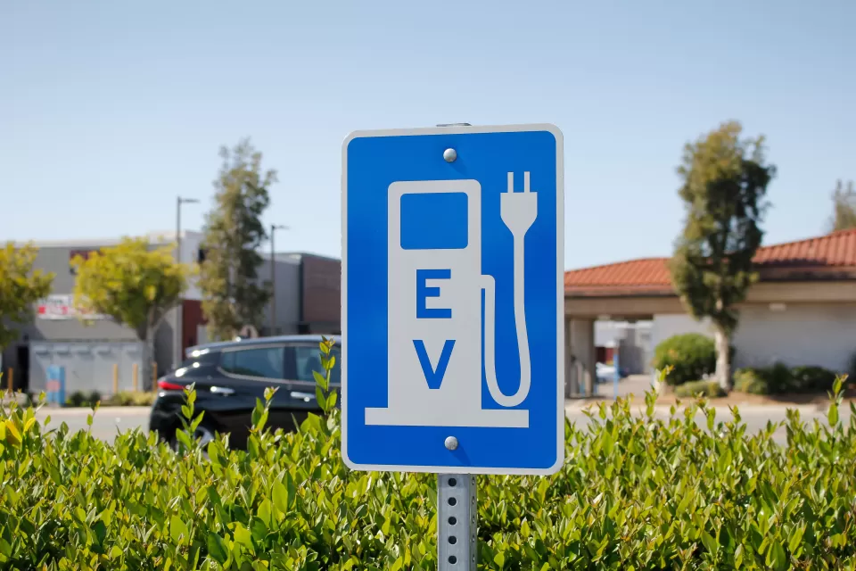 Blue sign with white gas pump symbol with electric plug and "EV"